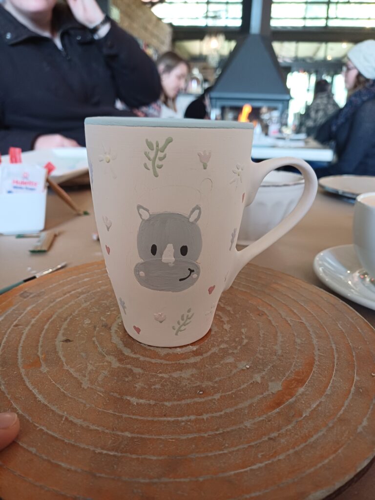 ceramic mug painted with a rhino and small flowers