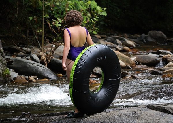 women carrying a tube to tube in a river